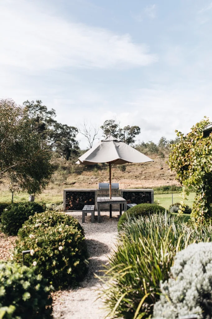 Garden wwith an outdoor dining area that has an umbrella to provide coverage.