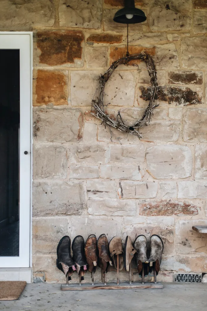 Sandstone shearer's cottage wwith a wreath hanging on the wall and boots placed underneath in a row.