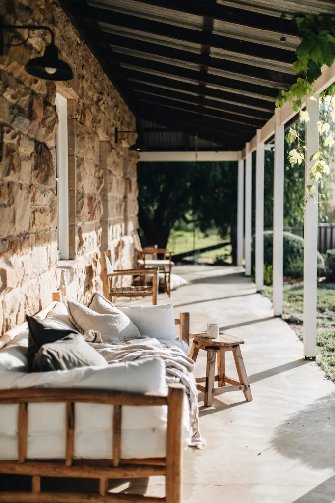 Sandstone shearer's cottage verandah with outdoor lounge and wooden stools