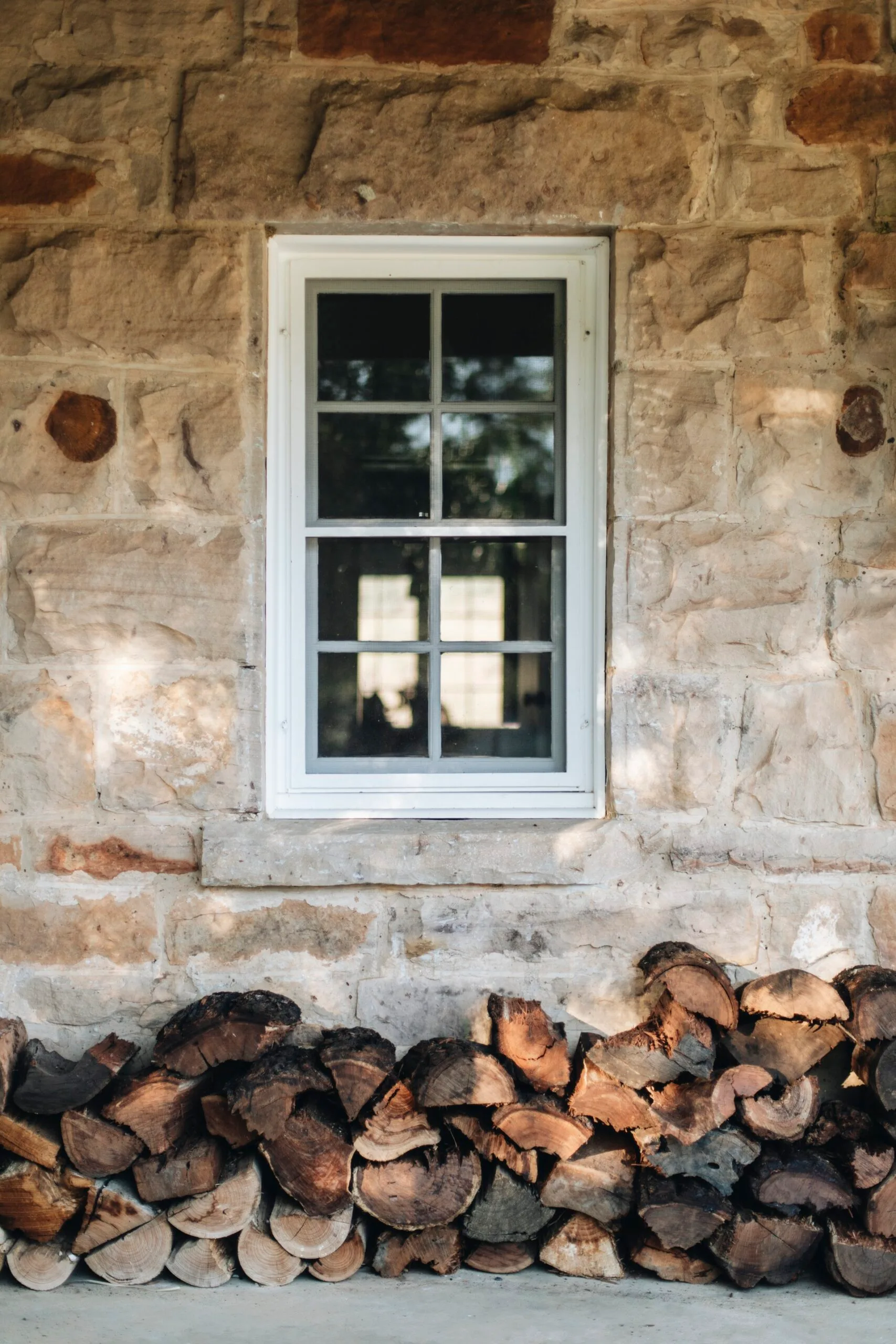 Sandstone shearer's cottage with a pile of fire wood beneath a window.