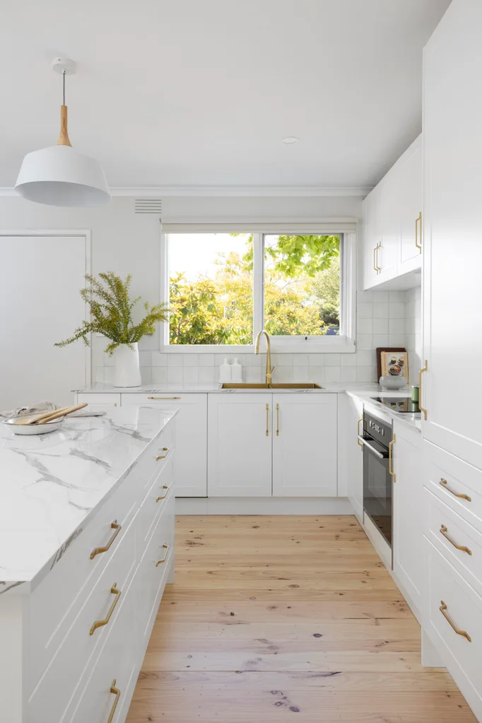 Proof that kitchen renovations can be budget-conscious, this newly renovated kitchen has timber floors, white cabinetry and white benchtops