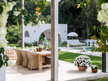 An alfresco dining area with yellow bougainvillea flowering on the pergola above it