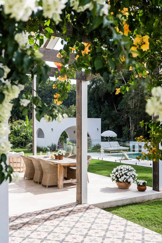 An alfresco dining area with yellow bougainvillea flowering on the pergola above it