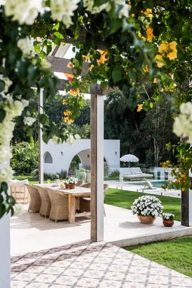 An alfresco dining area with yellow bougainvillea flowering on the pergola above it