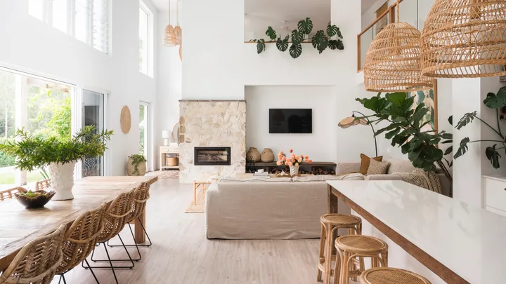 An open plan kitchen, dining and living area with mediterranean coastal style interiors, including white, reclaimed timber and a stone wall.