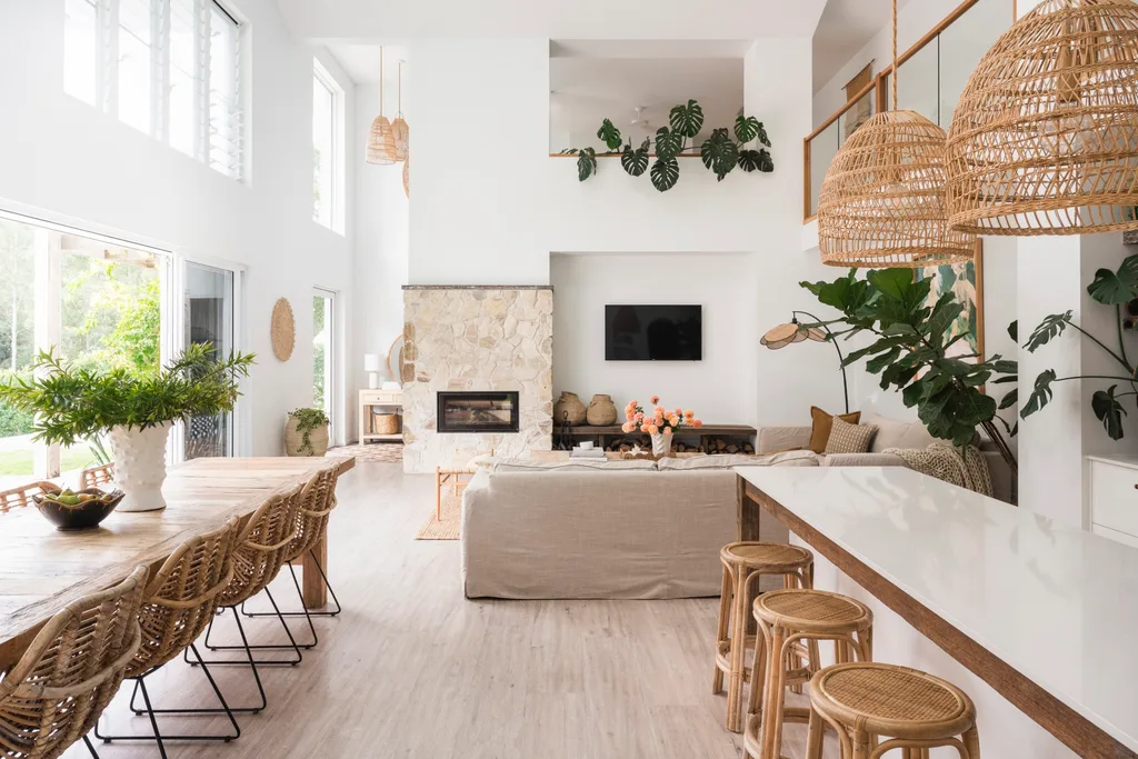 An open plan kitchen, dining and living area with mediterranean coastal style interiors, including white, reclaimed timber and a stone wall.