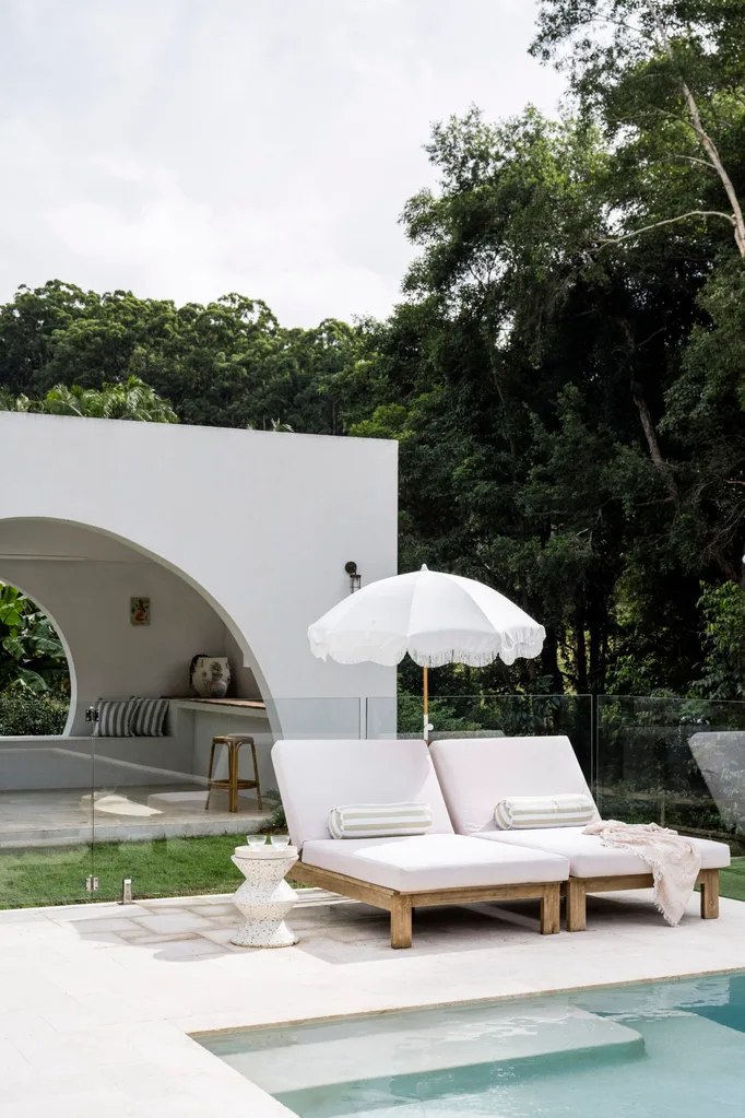 Two sun loungers beside a pool with a white beach umbrella