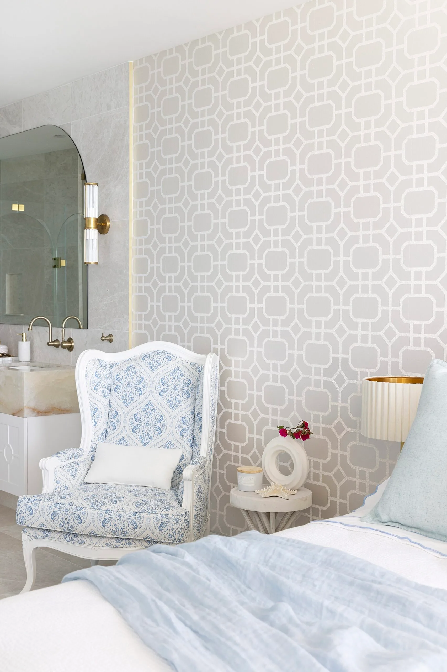 A blue and white wingback armchair beside a bed.