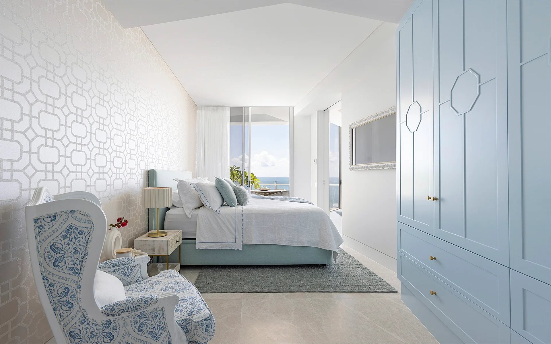 A blue bed base and headboard matches blue cabinetry and a white and blue armchair in this otherwise white bedroom.