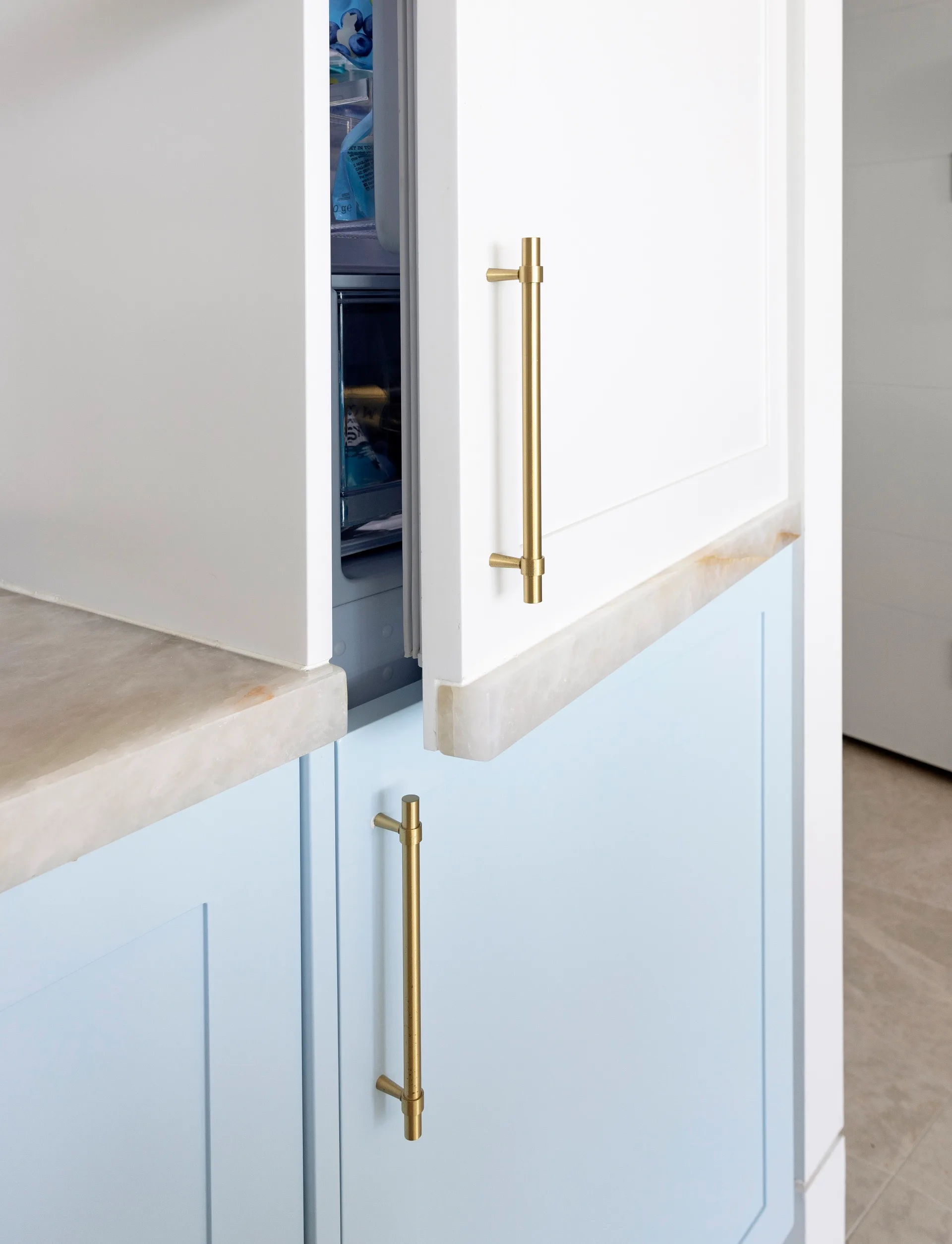 Blue and white kitchen cabinetry with brass handles.