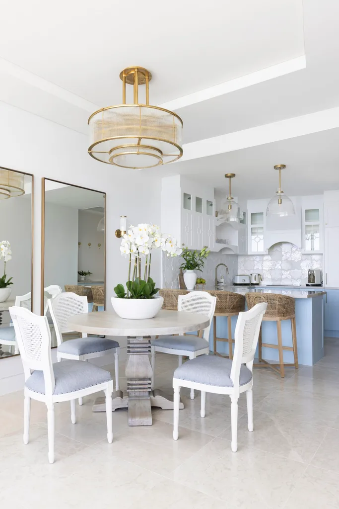 An open plan kitchen and dining area with a blue and white palette and rattan stools.