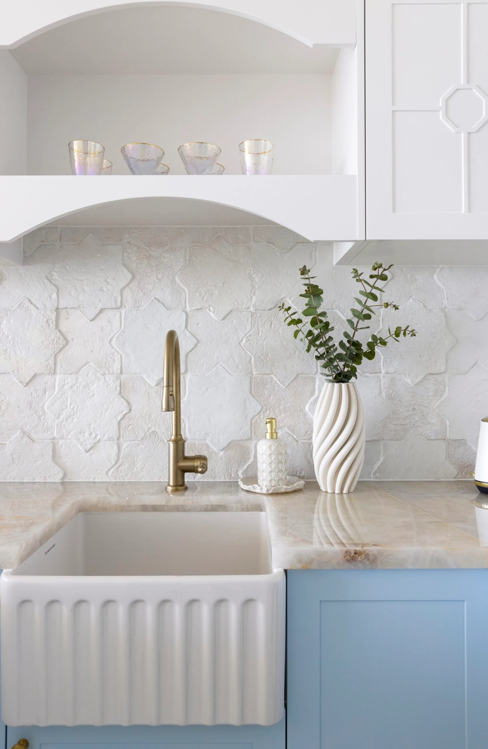 A white porcelain sink with a curved brass sink mixer.