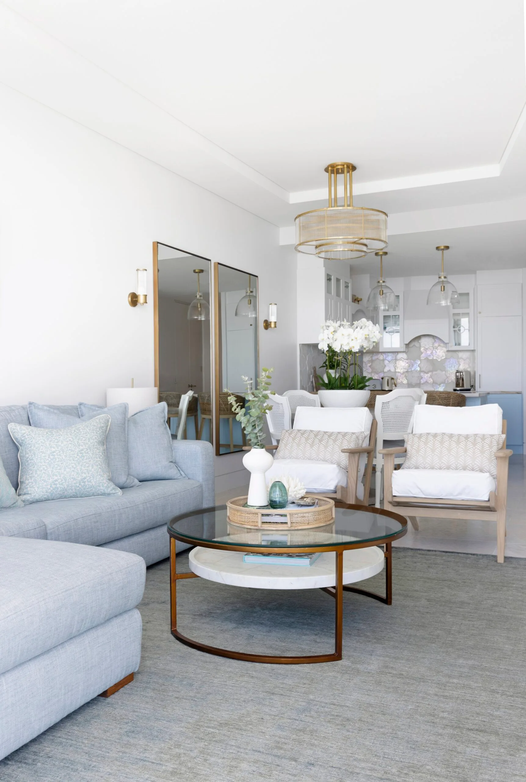 A living room with white armchairs, blue sofa and a circular coffee table.