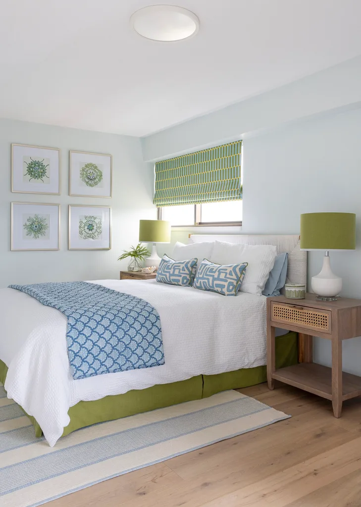 A bedroom with white bedlinen, blue cushions and a throw and a wooden bedside table.