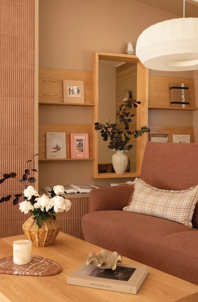 A home office with a terracotta toned sofa, natural oak coffee table and bookshelves decorated with interior design books