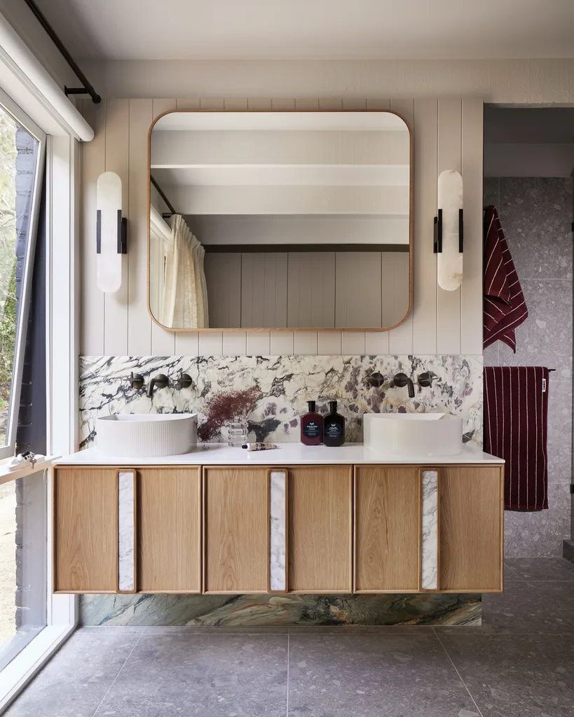 A bathroom with VJ panelling on the walls, a square mirror on the wall above the vanity, which has a marble splashback.