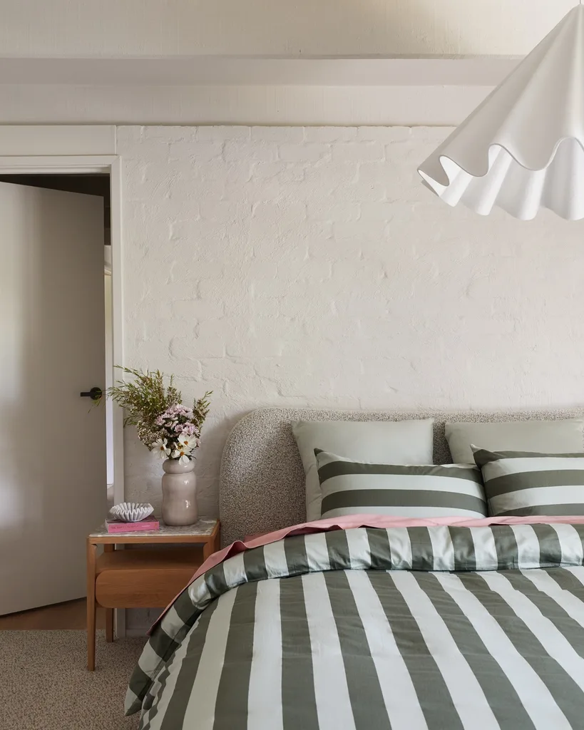 A bedroom in Bec Judd's Arthurs Seat holiday home with a fabric bedhead and stripey green quilt.