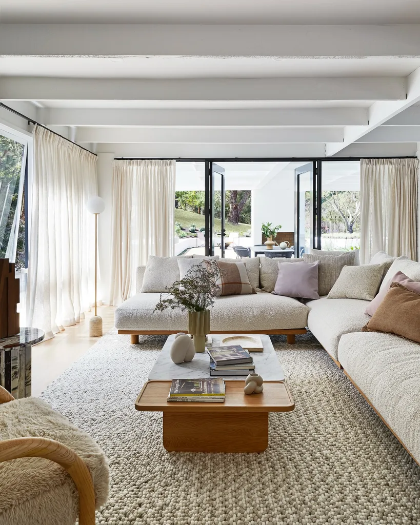 An open plan living area in Bec Judd's Arthurs Seat home, with a wooden console table, tactile fabric sofa and armchair and a marble and timber coffee table.