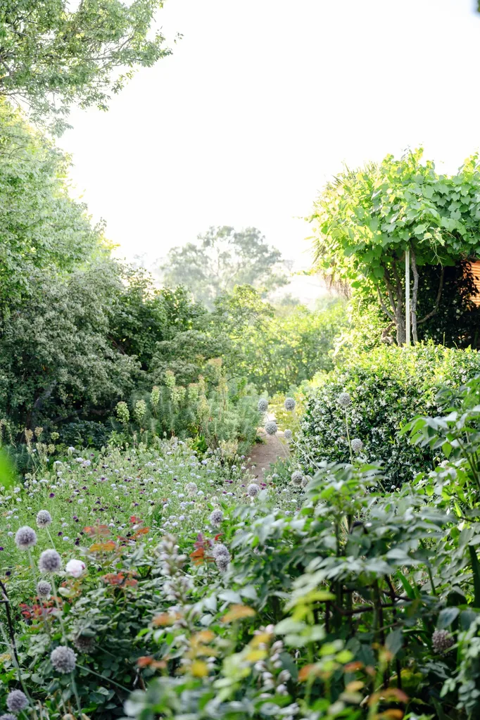 Rambling hedges and flower gardens create a soft border on either side of a path.