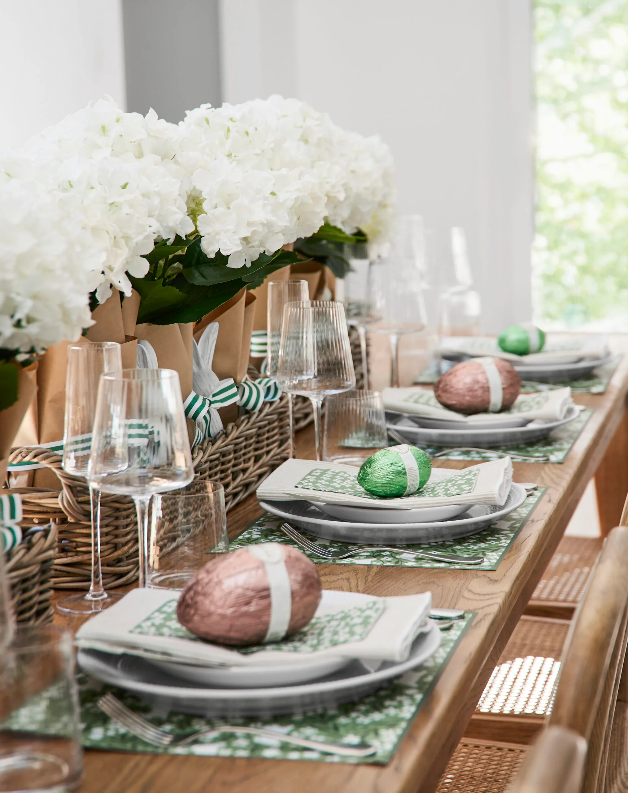 Indoor Easter table decorating with white hydrangea centrepiece and Easter eggs on place setting with white crockery