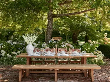 Outdoor Easter table decorating with large white vase and Easter themed place settings with white crockery on a timber outdoor dining table with timber bench seats