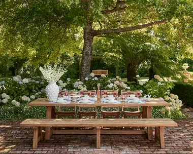 Outdoor Easter table decorating with large white vase and Easter themed place settings with white crockery on a timber outdoor dining table with timber bench seats
