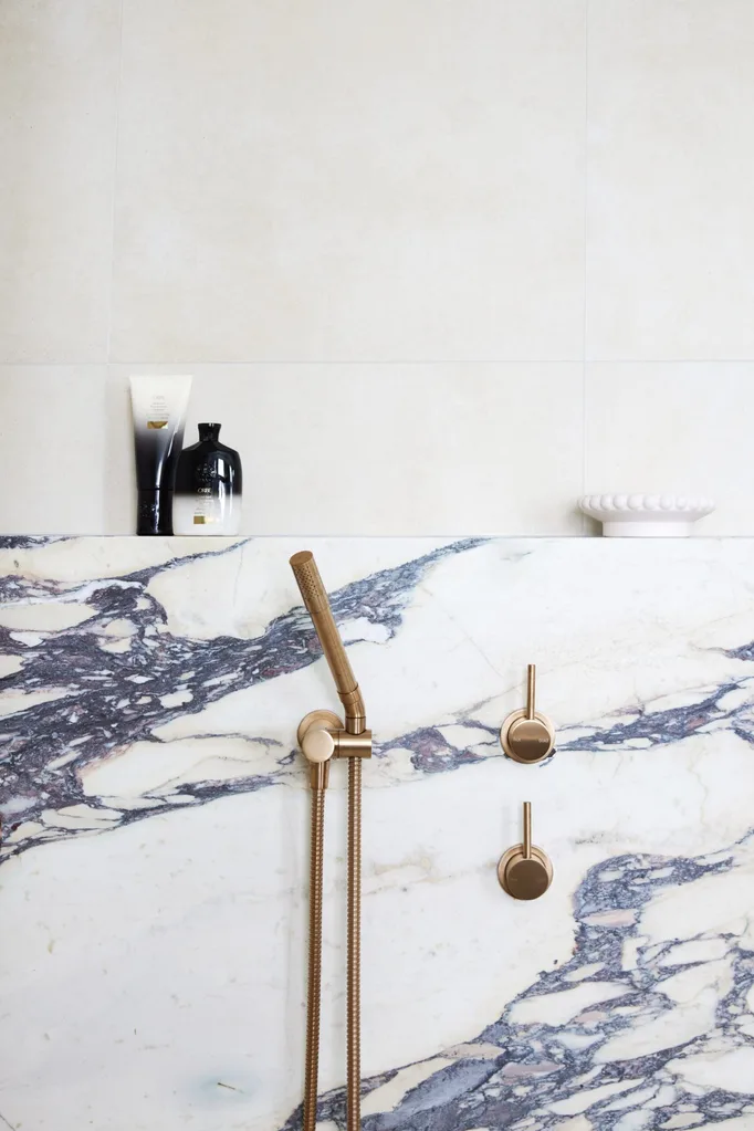 White and black marble wall with brass tapware.