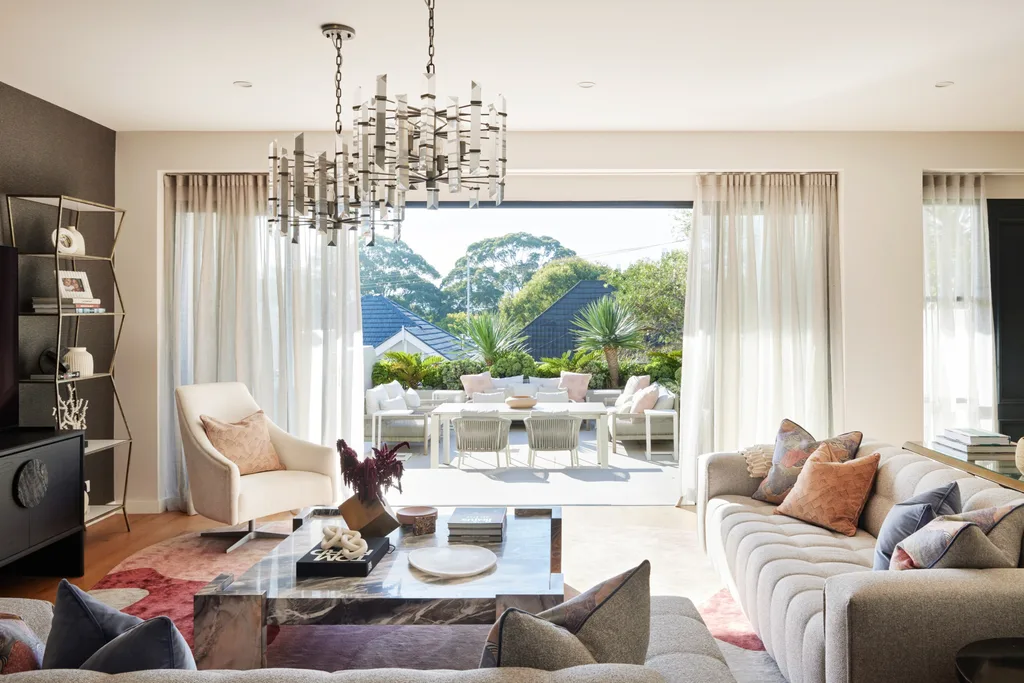 An open plan living room with a grey couch, marble coffee table and one wall painted white and one wall painted black. The sliding door opens to an outdoor living area.