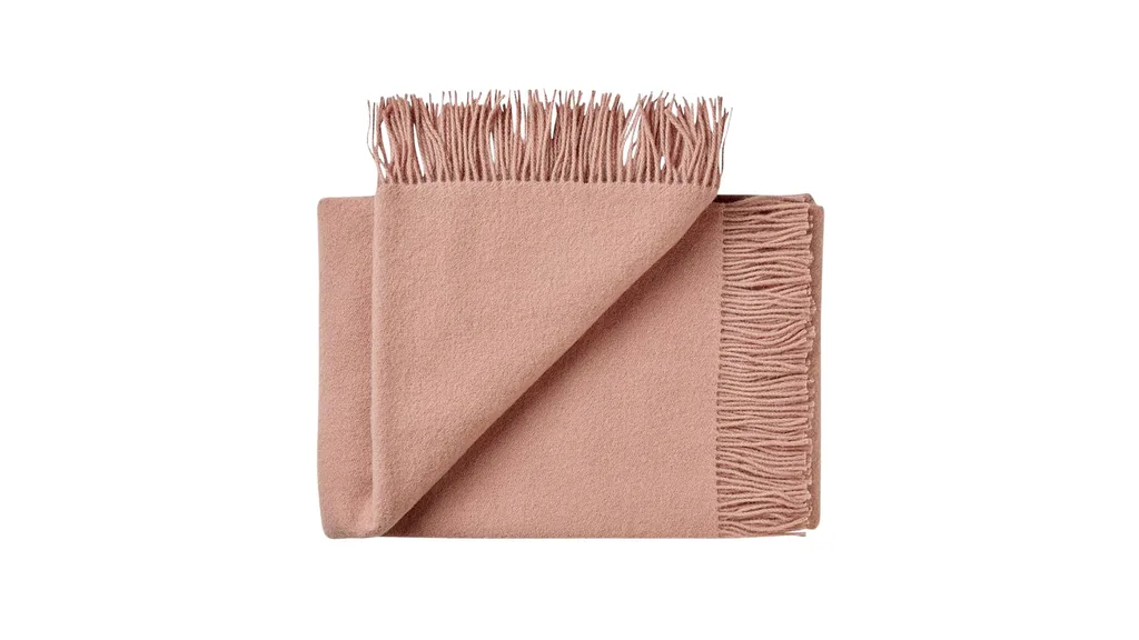 A rose coloured lambswool throw blanket.