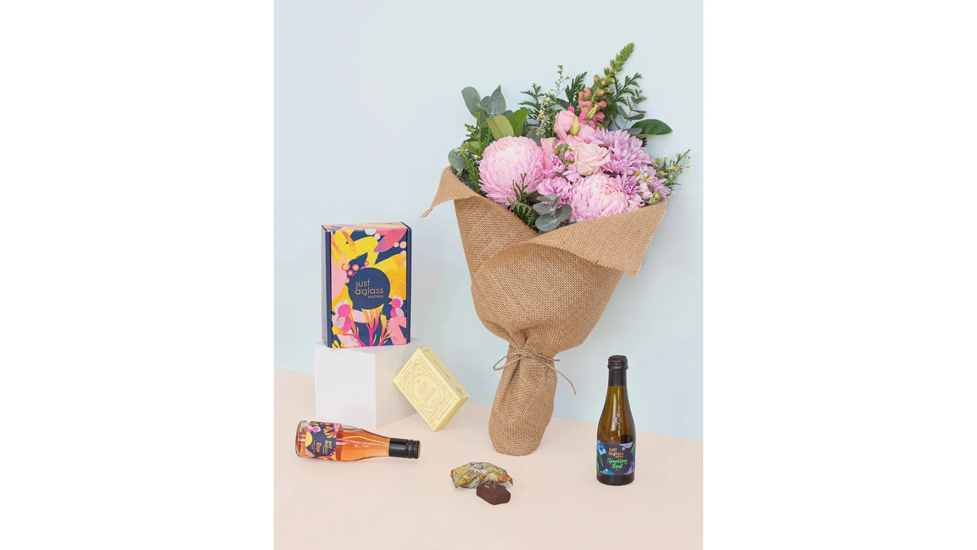 A gift set including a floral bouquet, chocolates and two bottles of wine.