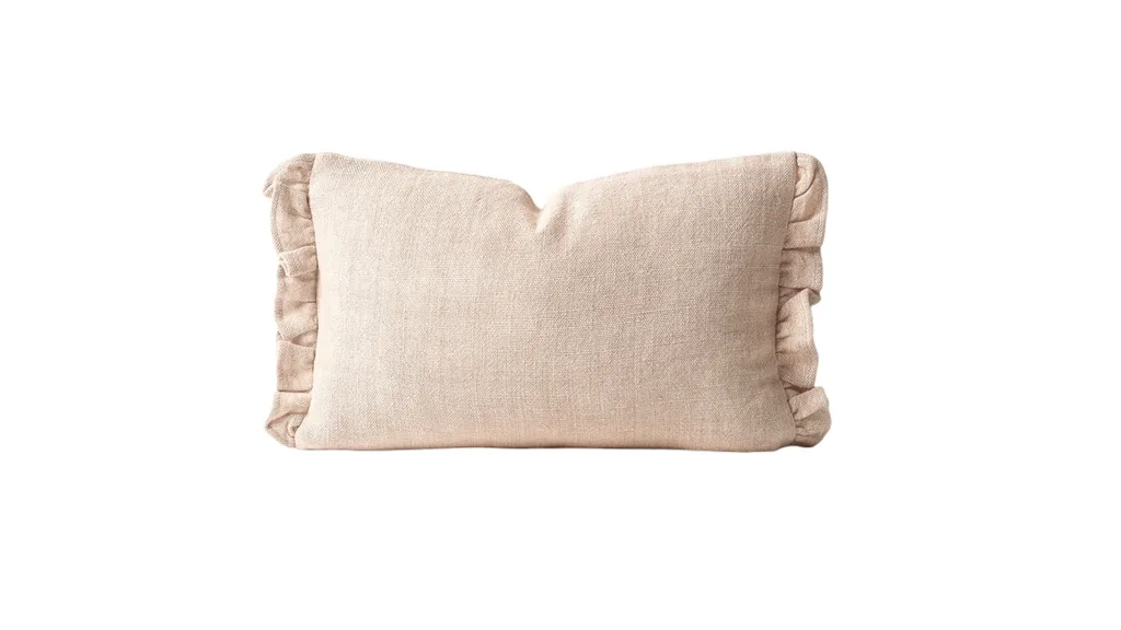 A linen pillow with a rectangular shape and ruffles on two sides in a neutral tone.