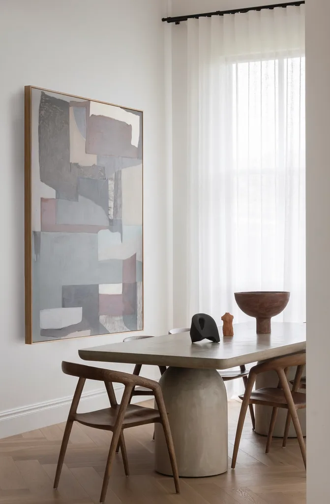 Neutral dining room with timber chairs, an earthy abstract artwork and sheer curtains