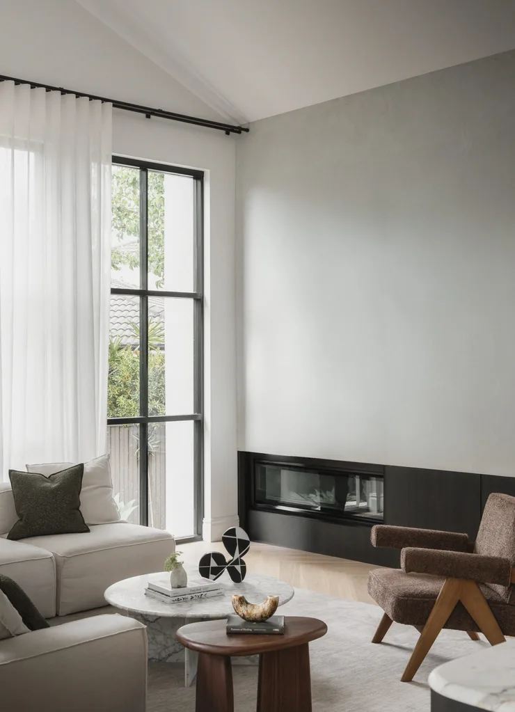 Neutral living room with a white sofa, black steel doors, fireplace, timber side table and marble coffee table