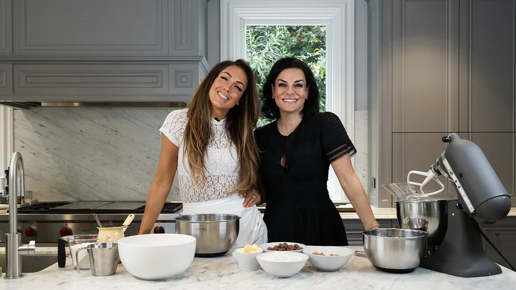 Victoria Montano and Nicole O'Neil from Real Housewives of Sydney cooking in Nicole's grey Hamptons-style kitchen.