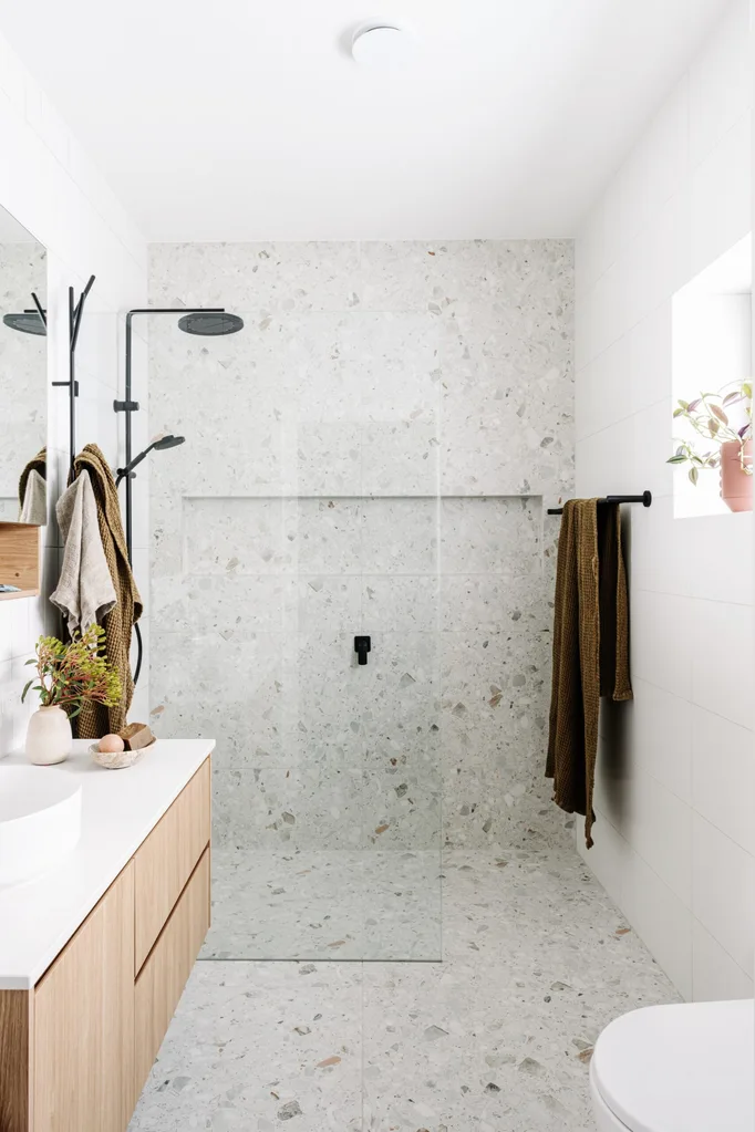 A bathroom in a certified passive house, good for bathroom renovation ideas that look to the future. A toilet and vanity are in the foreground with a shower in the background.