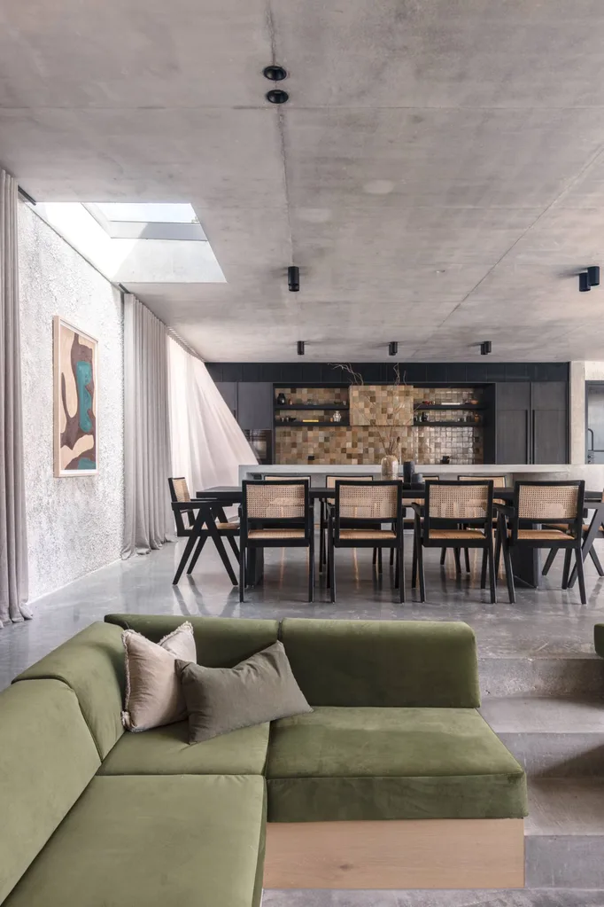 The sunken lounge with green cushions at Bunker Byron with concrete floors