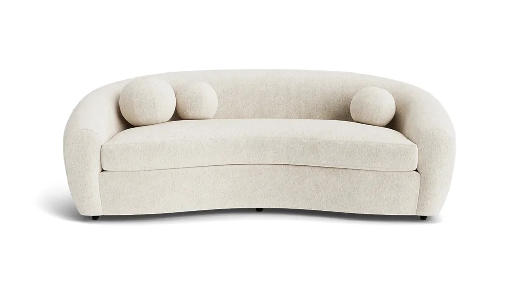 A curved fabric sofa from Coco Republic with three spherical cushions.