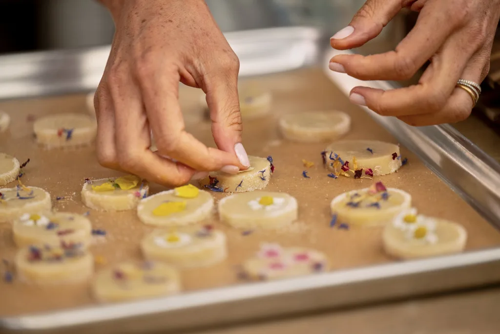 Close up of Meghan's hand putting flowers on shortbread before baking