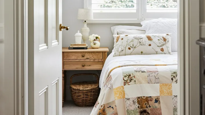 alexandra nea's bedroom featuring a timber bedside table, patchwork quilt and plantation shutters