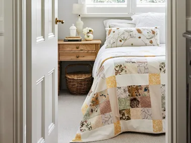 alexandra nea's bedroom featuring a timber bedside table, patchwork quilt and plantation shutters