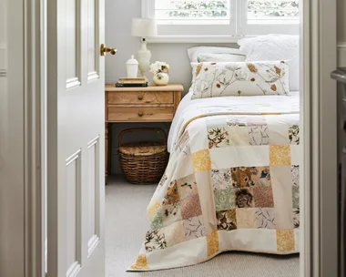 alexandra nea's bedroom featuring a timber bedside table, patchwork quilt and plantation shutters
