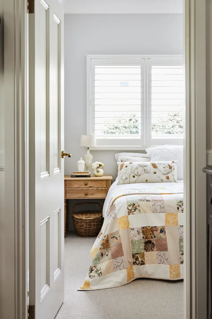 alexandra nea's bedroom featuring a timber bedside table, patchwork quilt and plantation shutters
