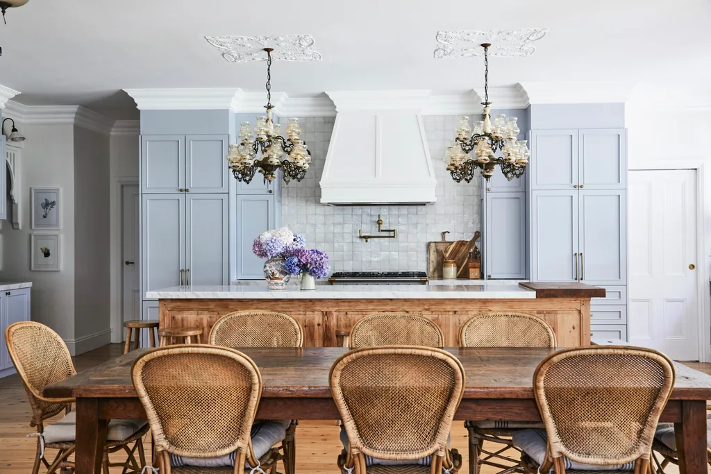 alexandra nea's kitchen with light grey joinery, and oak dining table and wicker chairs, plus a vintage chandelier