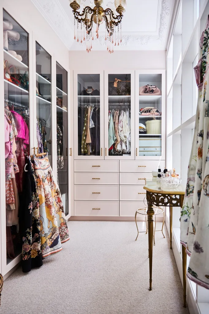 alexandra nea's pink walk-in wardrobe with a vintage chandelier, antique hall table, glass doors and cornices