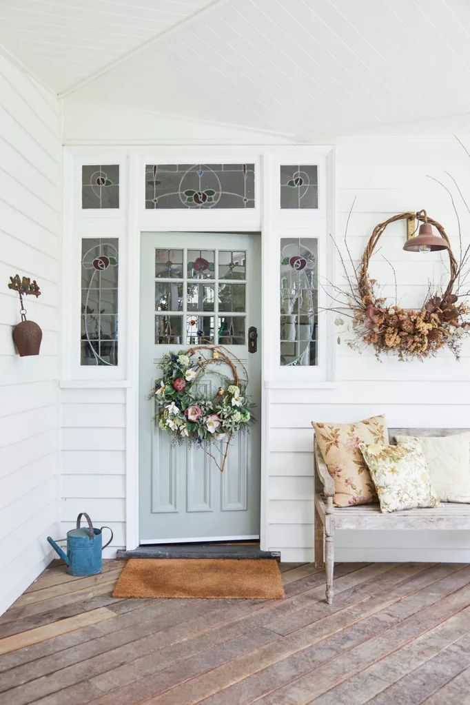 alexandra nea's white weatherboard house featuring a heritage verandah and grey-green door with antique wall lights