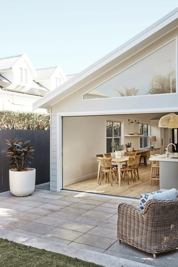 The rear exterior of a home after a modern extension with an open plan kitchen and dining area leading to the alfresco areas.