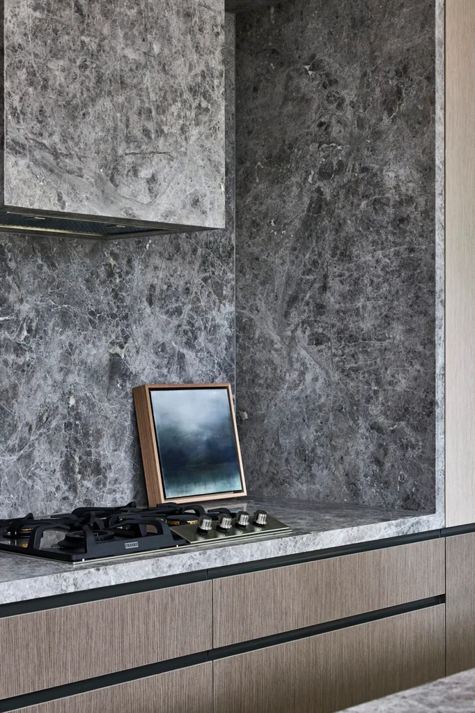 Grey marble splashback, rangehood and benchtop, surrounded by Eveneer joinery in two tones.