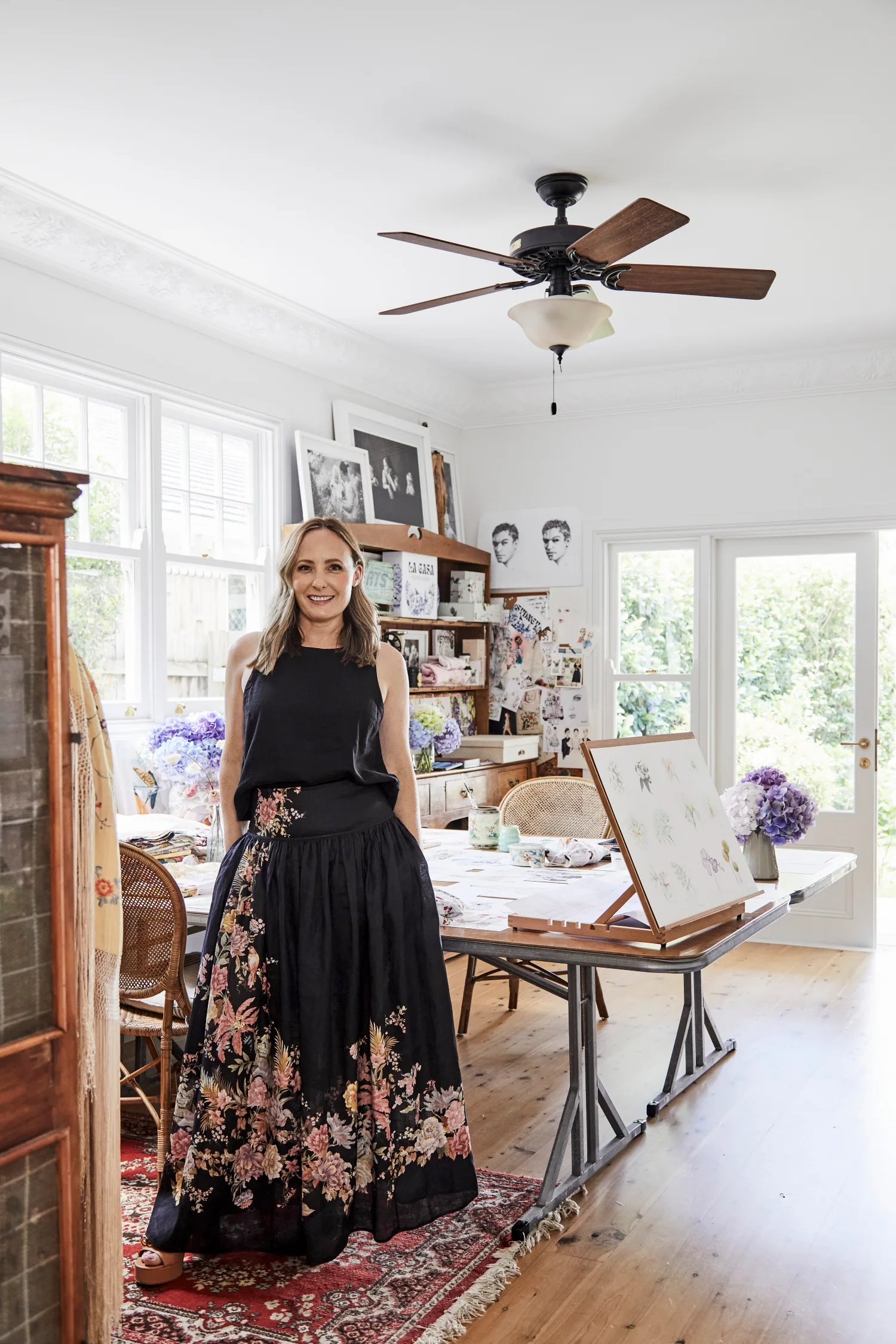 Illustrator Alexandra Nea Graham in her home studio standing beside a table
