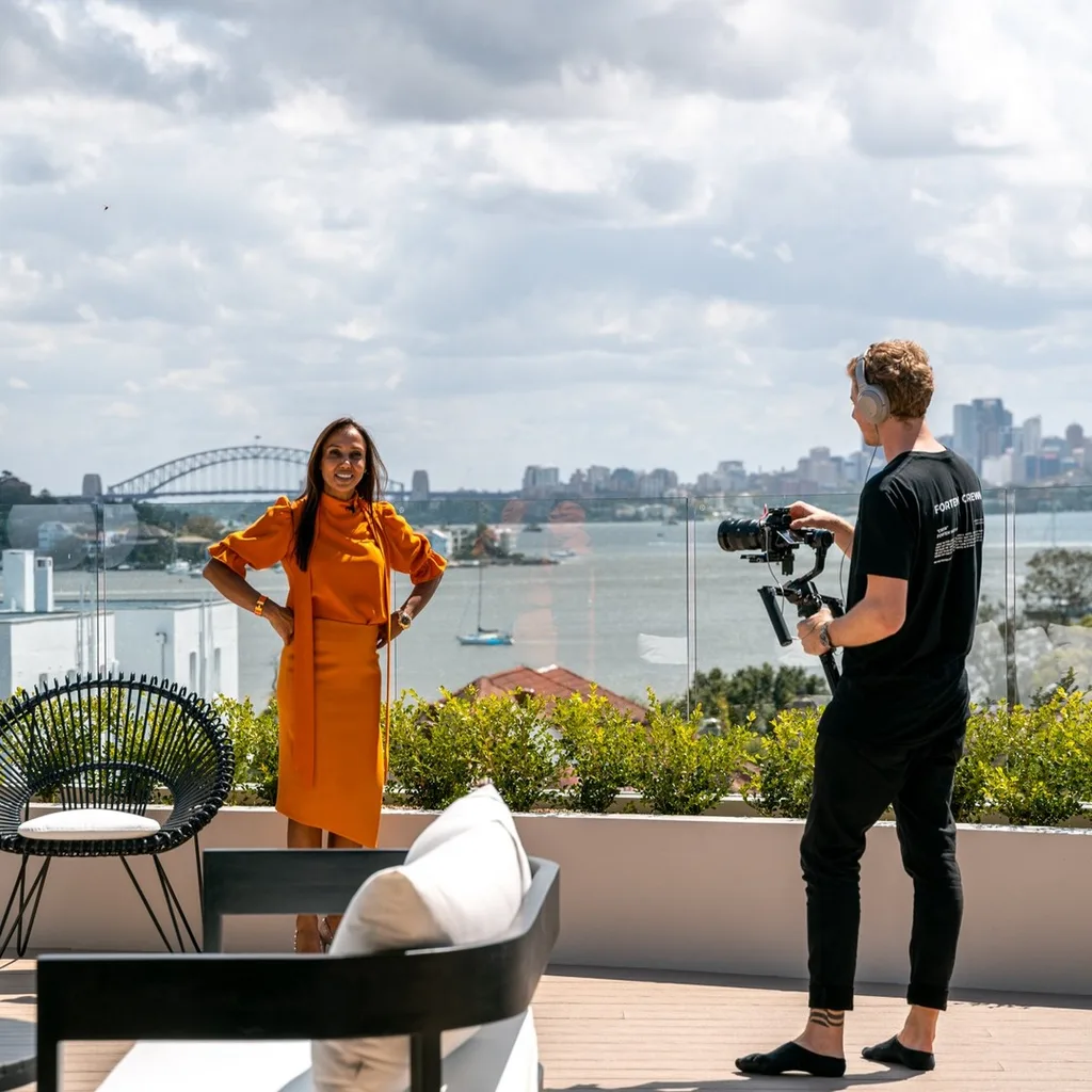 Luxe Listings Sydney agent D'Leanne Lewis standing at a view with the Opera House and a camera person