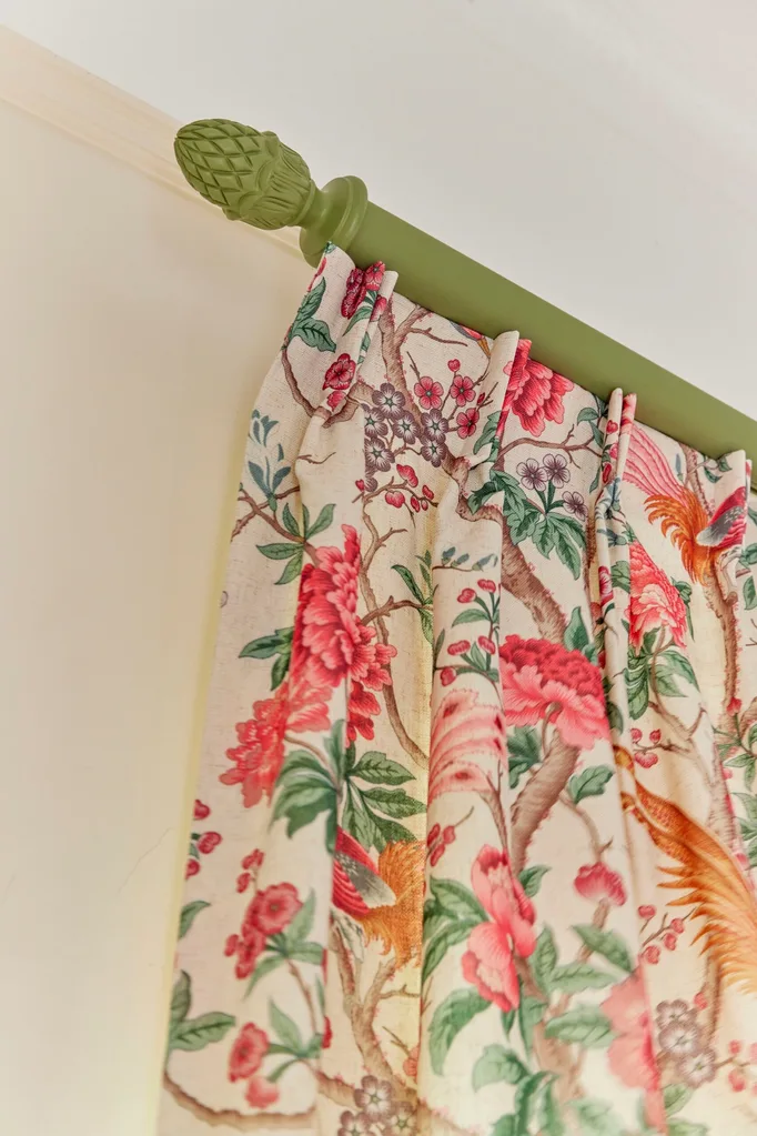 A green curtain rod and patterned curtain.